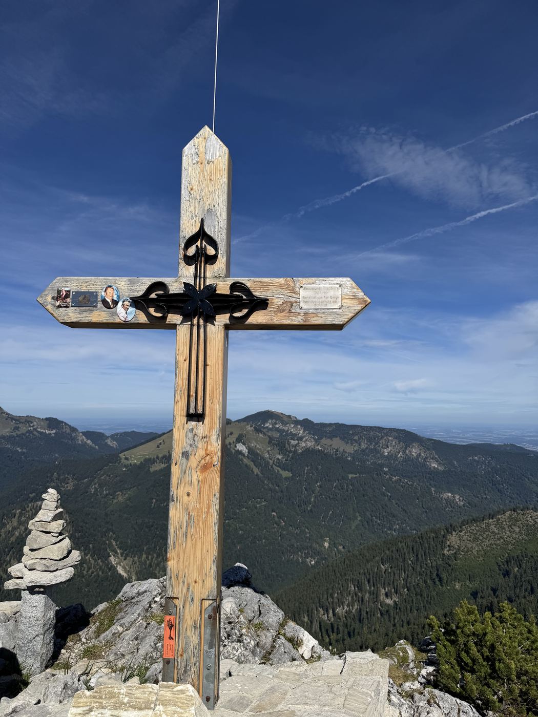 Gipfelkreuz mit waagerechtem Schild und Plaketten, daneben ein gesetzter Steinmann.